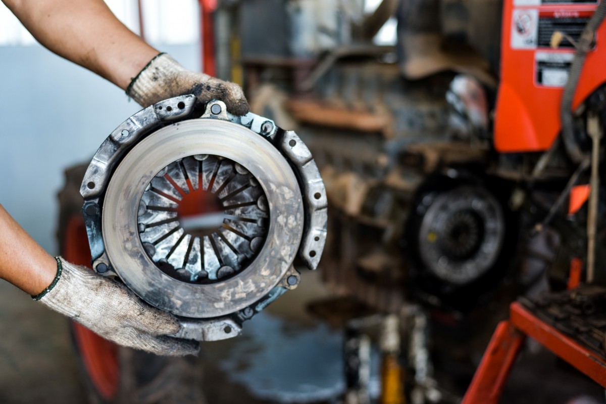 mechanic with gloves on holding transmission parts